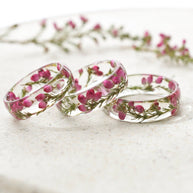 Three transparent rings with pink flowers on a white marble surface