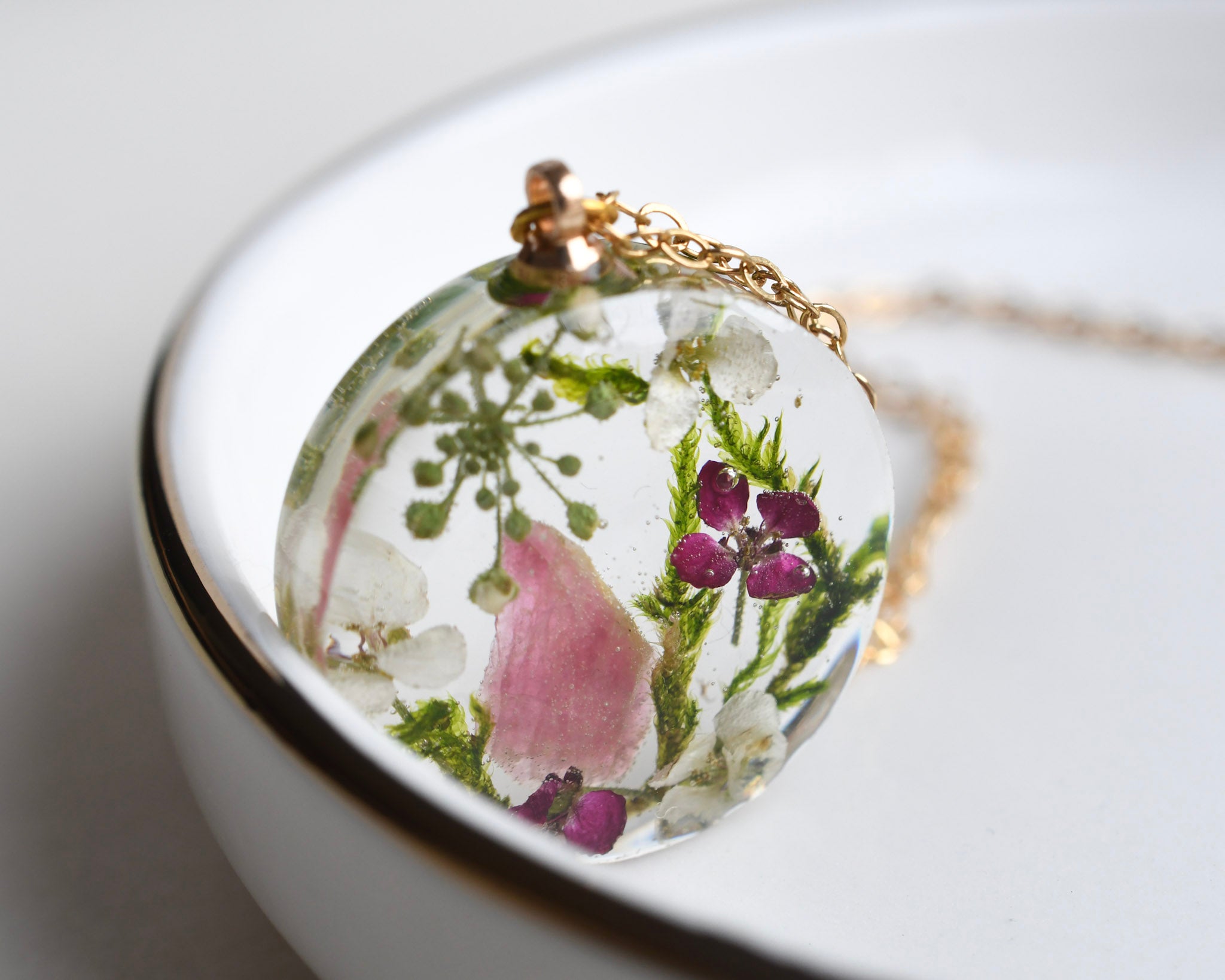 Close-up of terrarium pendant with real moss, alyssum flowers, and pink tourmaline