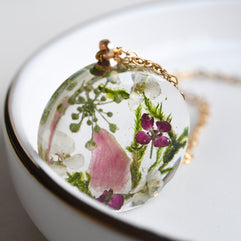Close-up of terrarium pendant with real moss, alyssum flowers, and pink tourmaline