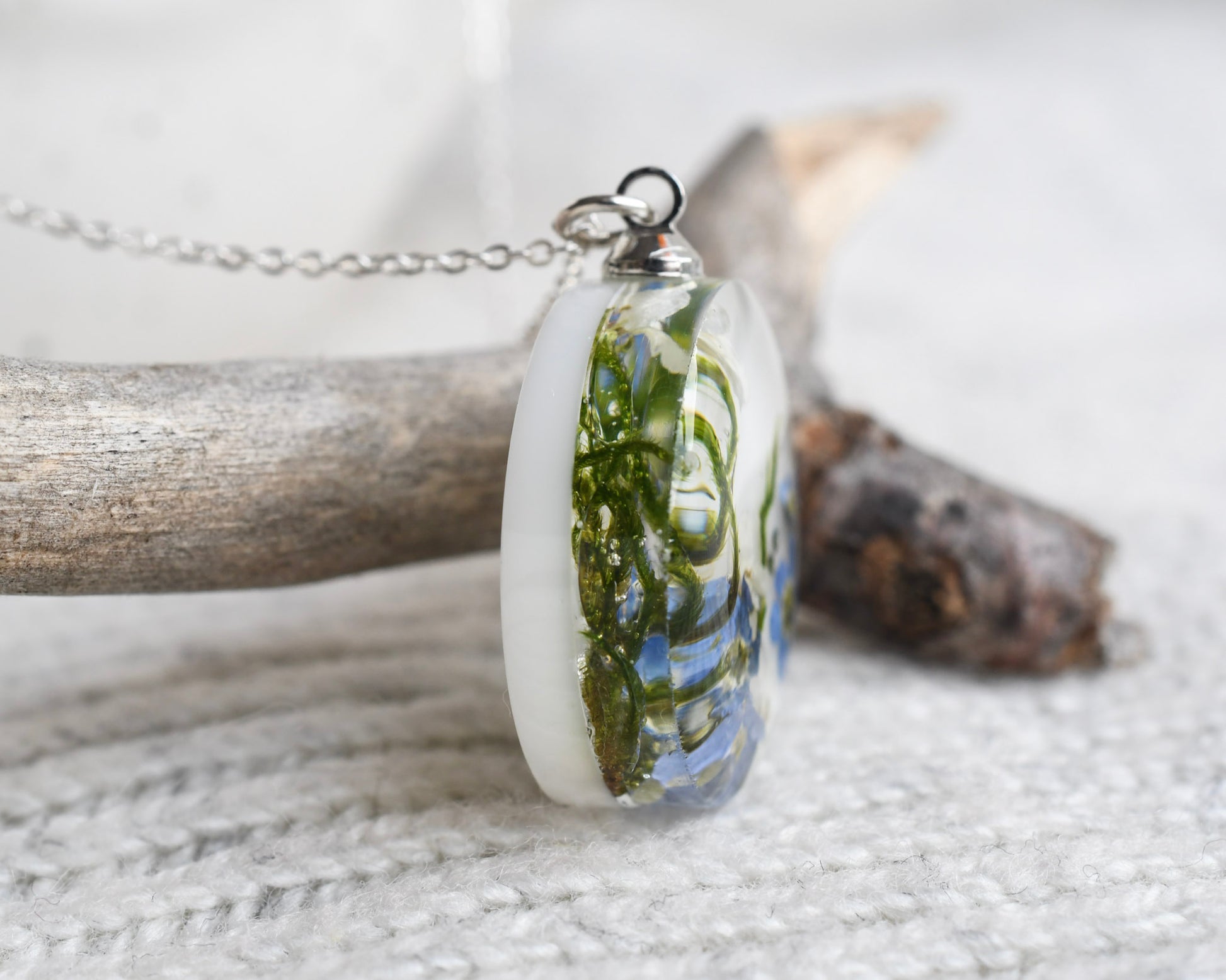 Necklace with a pendant featuring green leafy design on a light background