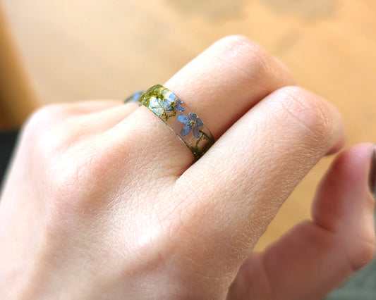 Close-up of a hand wearing a ring with floral design on a blurred background