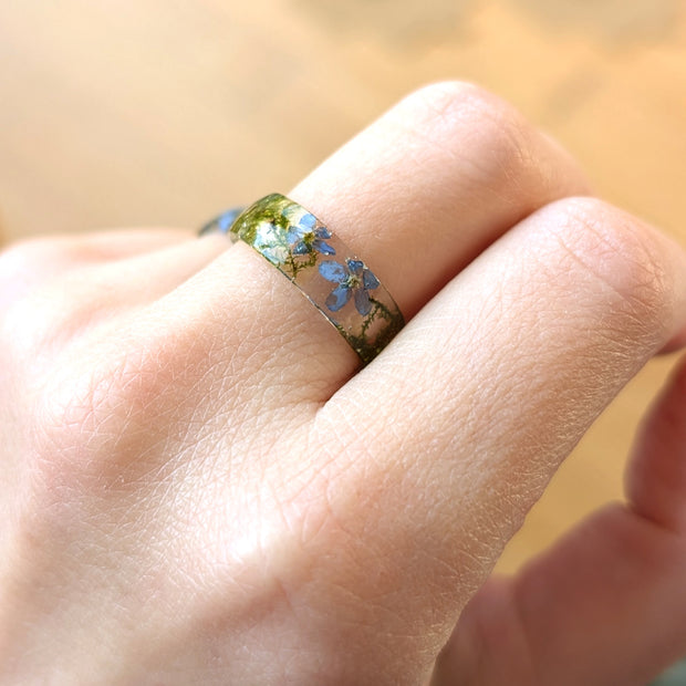 Close-up of a hand wearing a ring with floral design on a blurred background