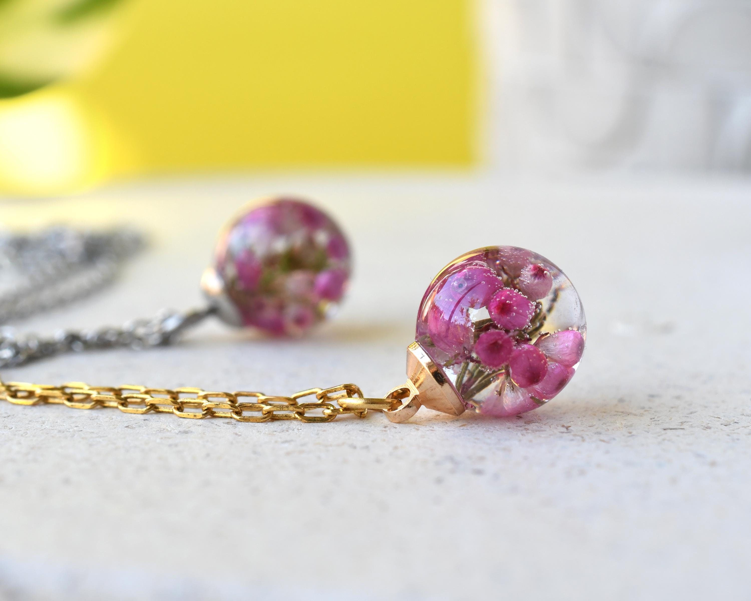 Flatlay of Pink Glade Necklace with real pink heather in resin globe