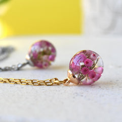 Flatlay of Pink Glade Necklace with real pink heather in resin globe