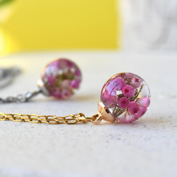 Flatlay of Pink Glade Necklace with real pink heather in resin globe
