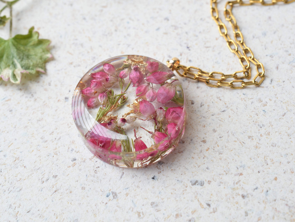 Round resin necklace with pink heather and shimmering gold flakes
