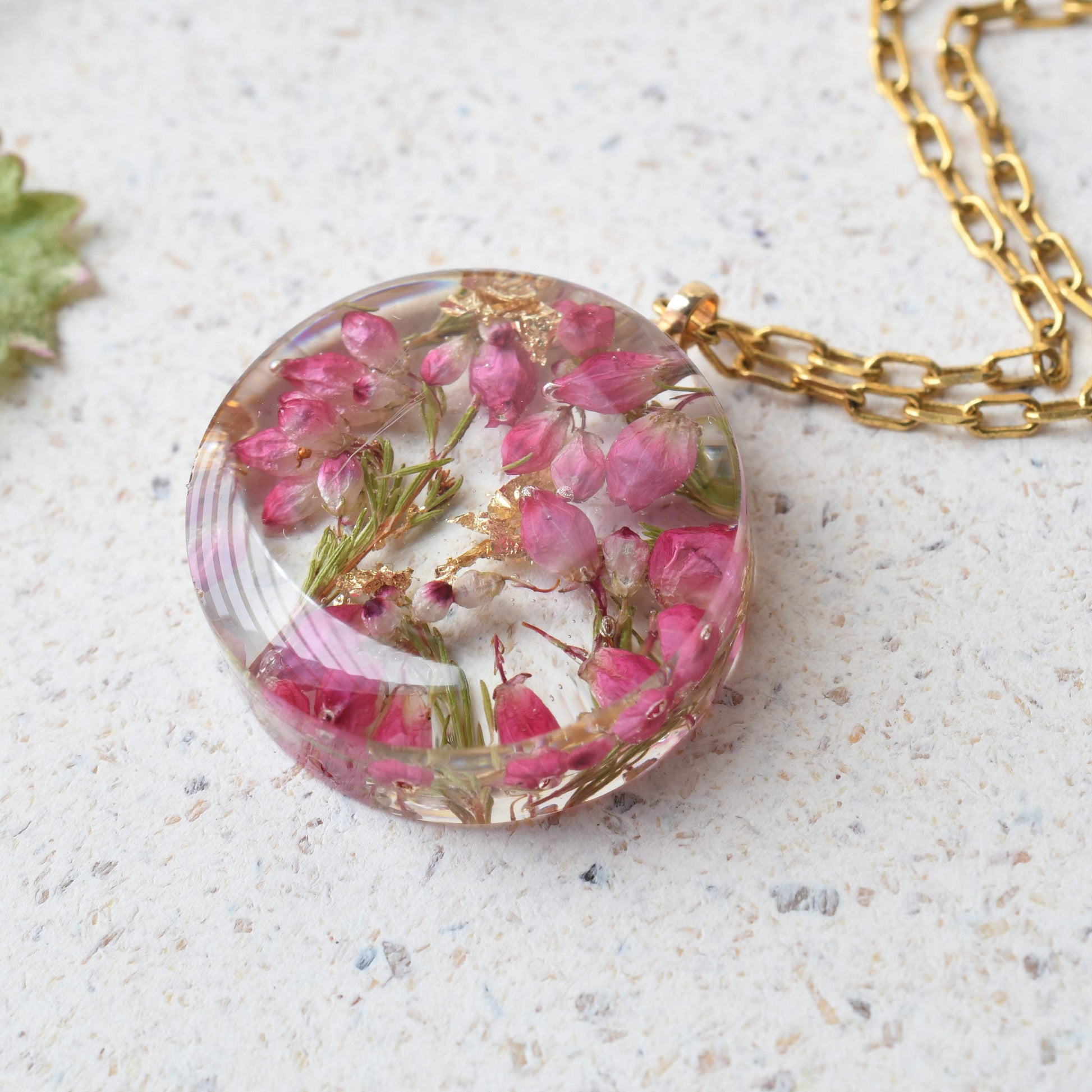 Round resin necklace with pink heather and shimmering gold flakes