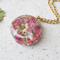 Round resin necklace with pink heather and shimmering gold flakes