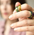 Close-up of a hand wearing colorful rings with a blurred background