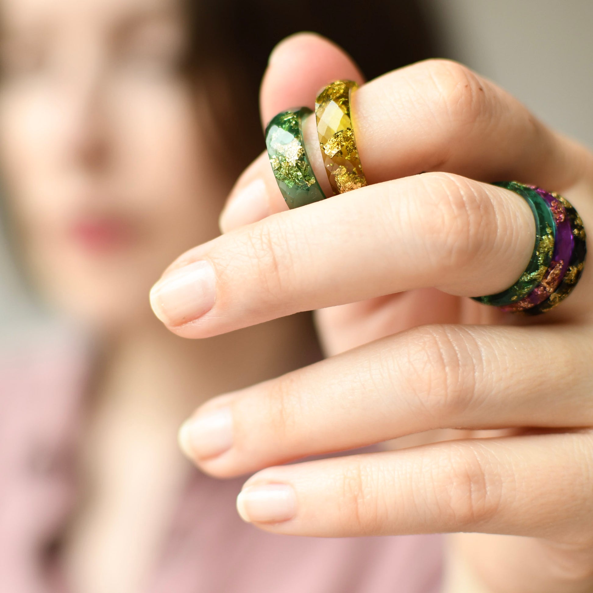 Close-up of a hand wearing colorful rings with a blurred background