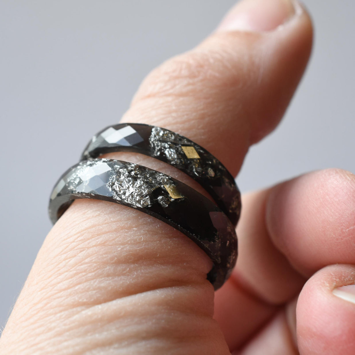 Matching black and silver resin rings worn on hands — handmade jewelry