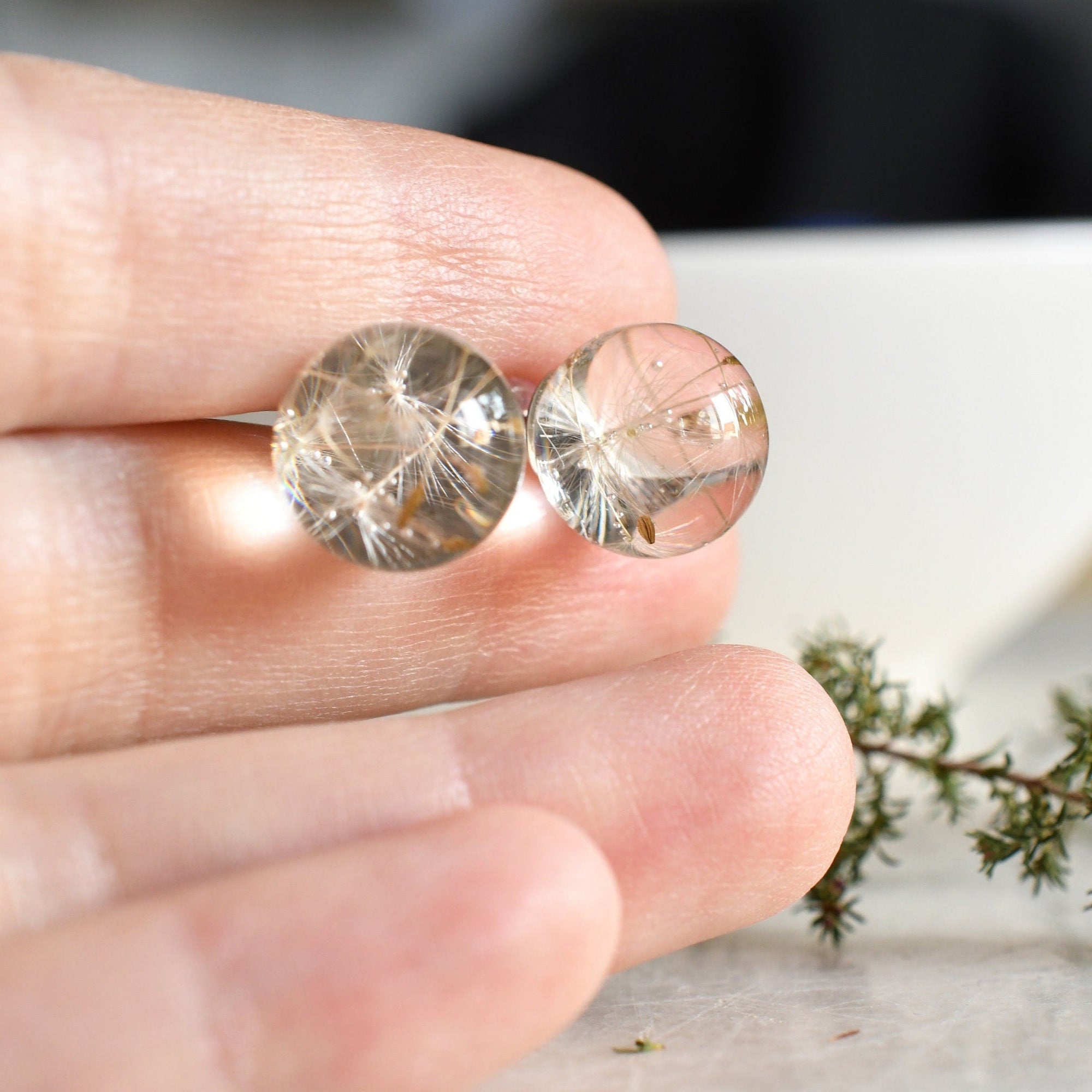 Dandelion resin stud earrings held in hand — delicate handmade jewelry