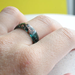 Handmade emerald green resin ring worn on hand — modern birthstone jewelry
