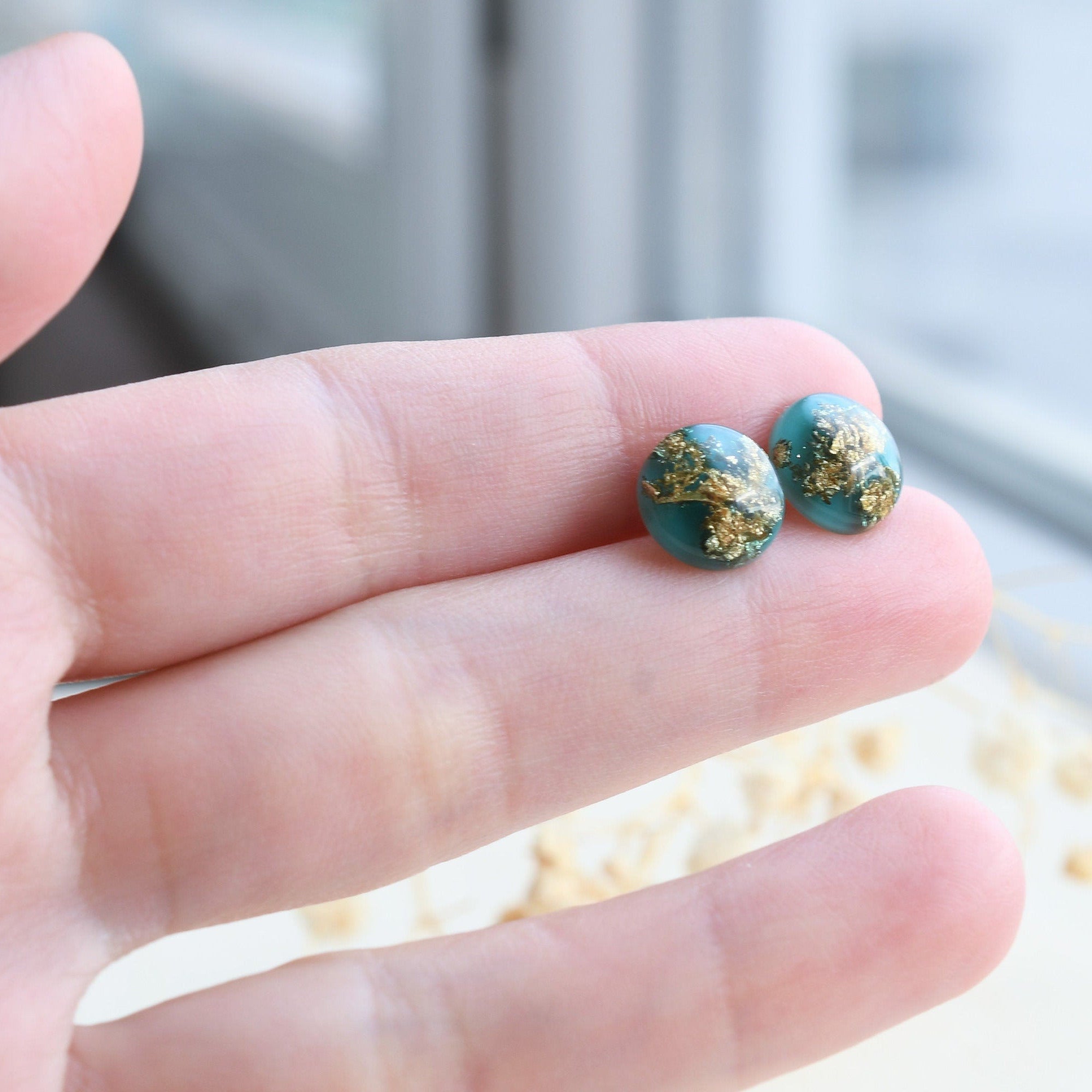 Handmade emerald green resin stud earrings worn on ear — minimalist jewelry