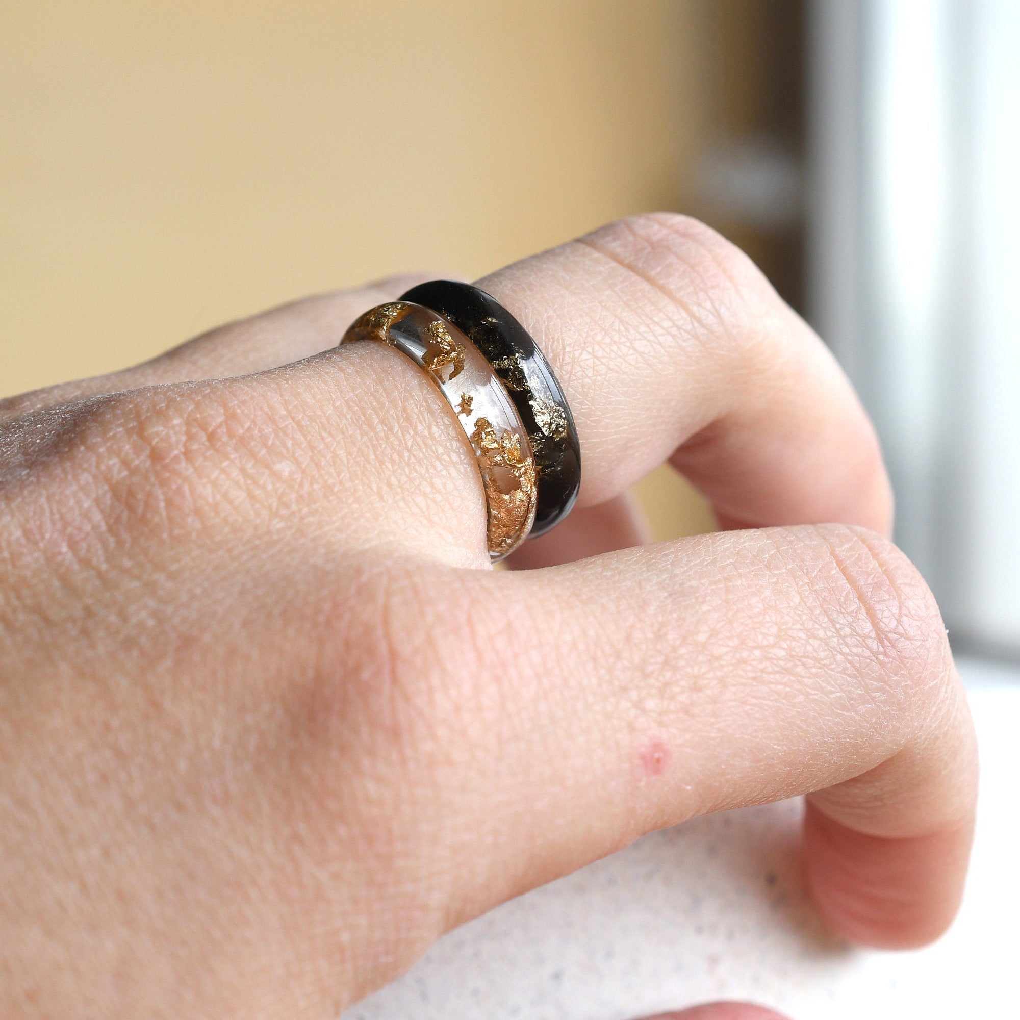 Matching smooth black and clear resin couple rings worn on hands