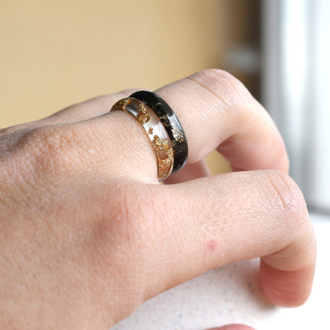 Matching smooth black and clear resin couple rings worn on hands