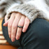 Close-up of a hand wearing a ring with a textured sleeve and dark pants.