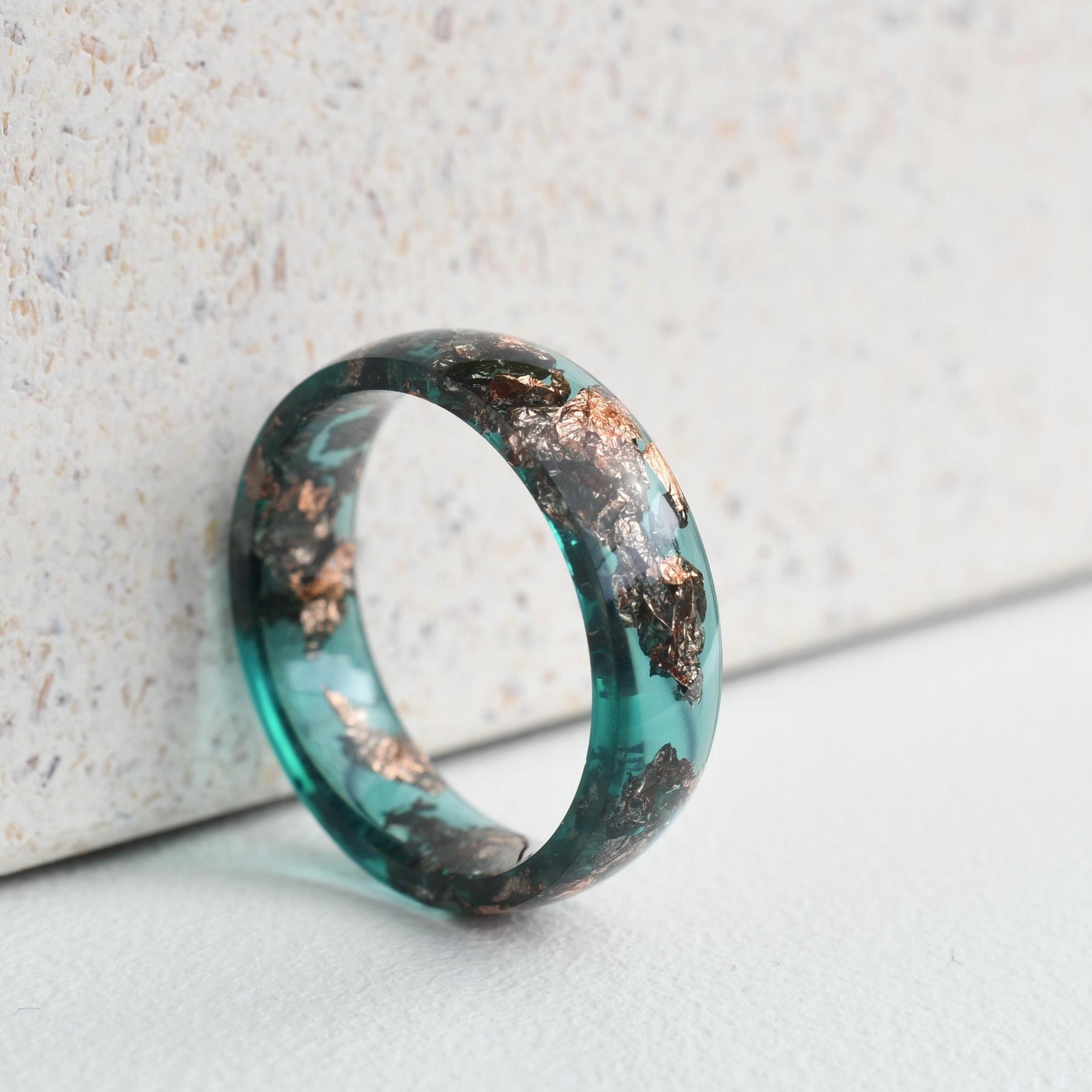 Green wooden ring with copper inlay on a light gray surface