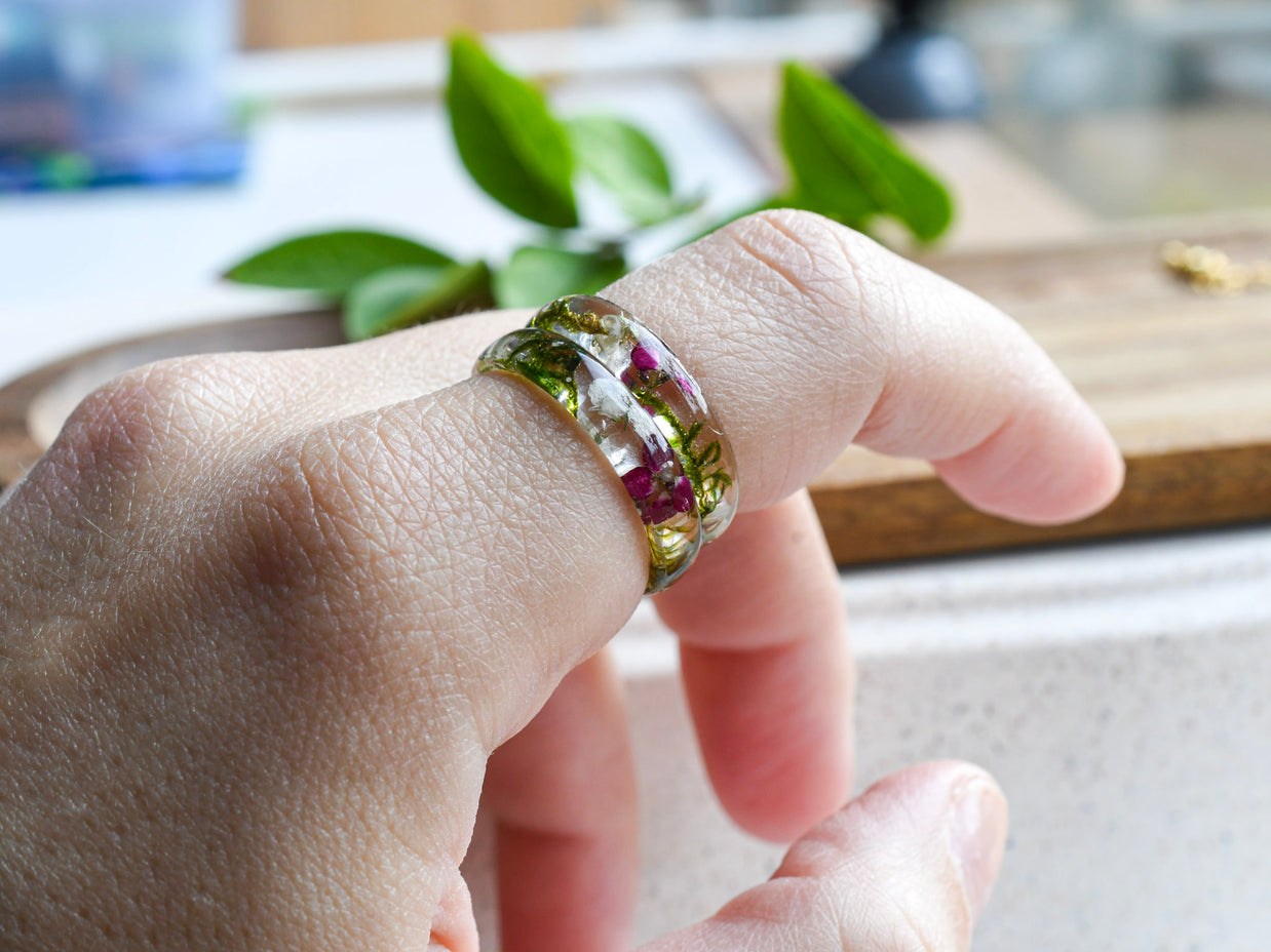 Handmade moss and alyssum resin ring worn on hand — nature-inspired design
