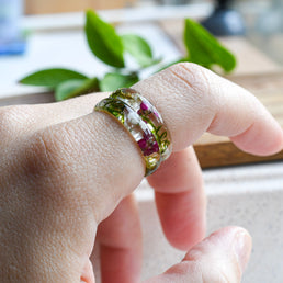 Handmade moss and alyssum resin ring worn on hand — nature-inspired design