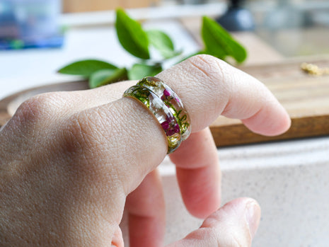 Handmade moss and alyssum resin ring worn on hand — nature-inspired design