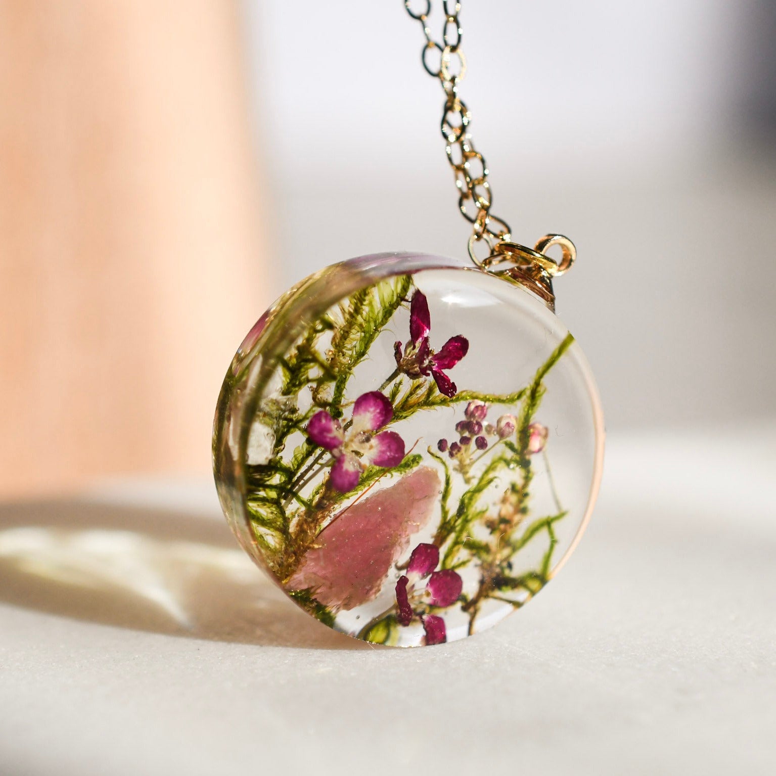 Moss and pink crystal resin necklace in sunlight