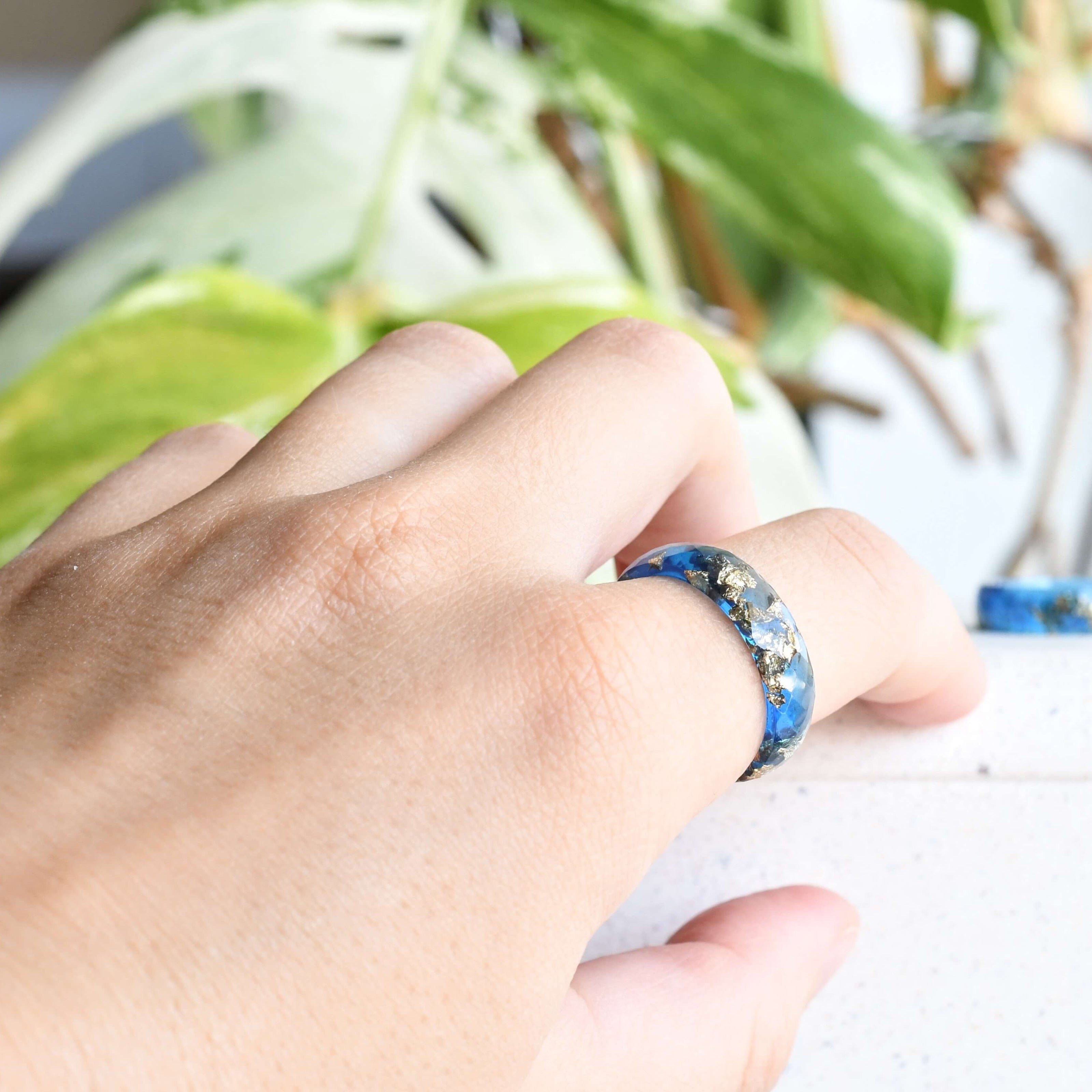 Sapphire blue resin ring with gold flakes worn on hand — unisex minimalist jewelry