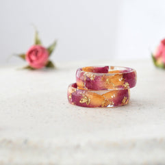 Resin ring with rose petals and gold leaf shown flat on soft background