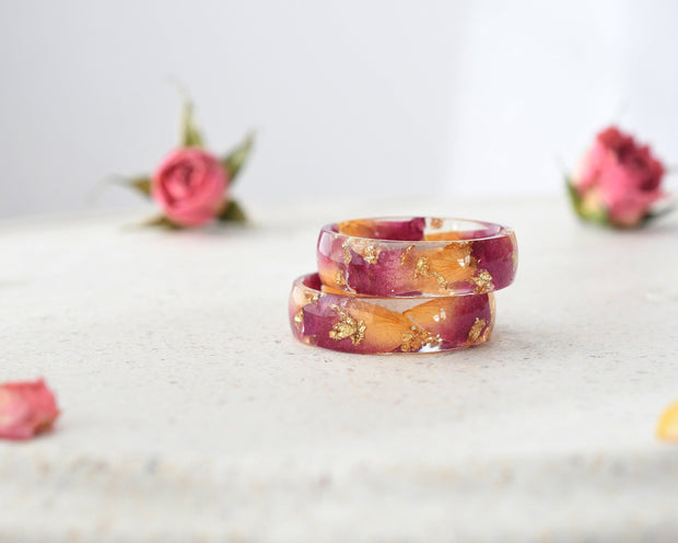Resin ring with rose petals and gold leaf shown flat on soft background