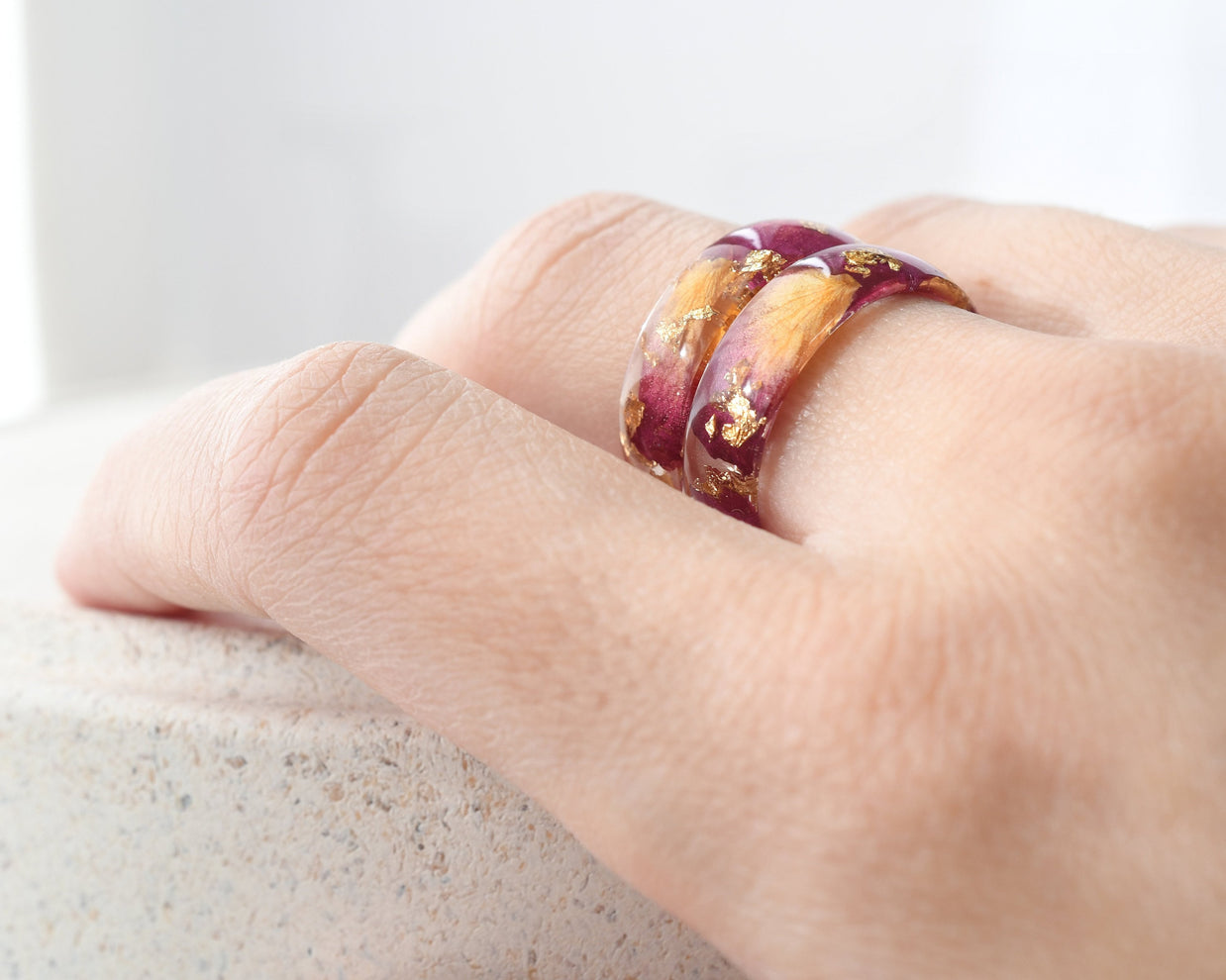 Hand wearing a ring with a gradient design on a light background