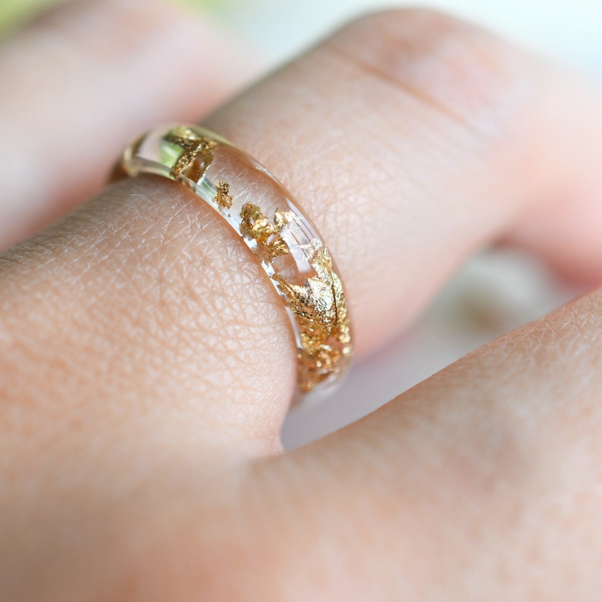Gold ring on a person's finger with a blurred background