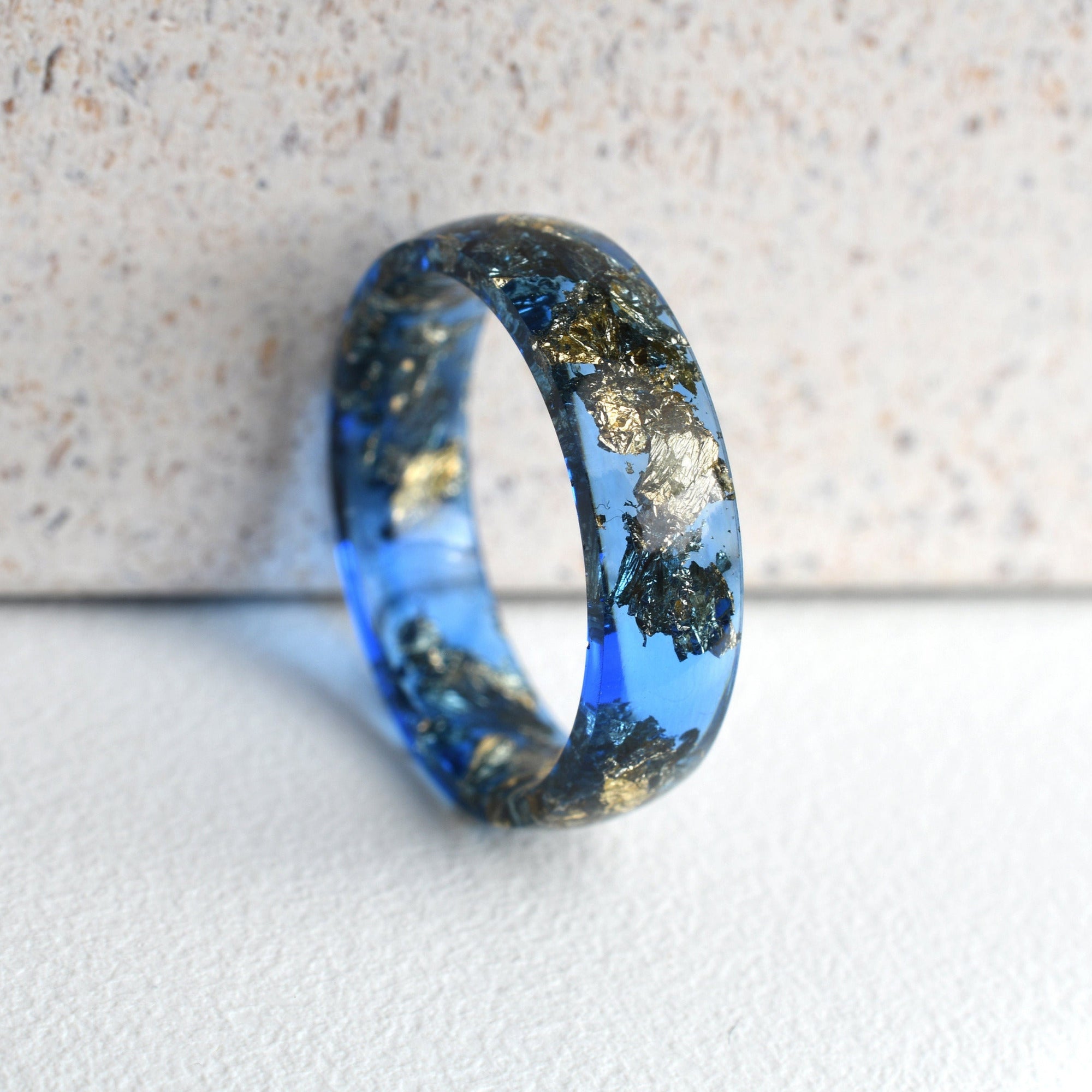 Close-up of gold leaf details suspended in sapphire resin ring
