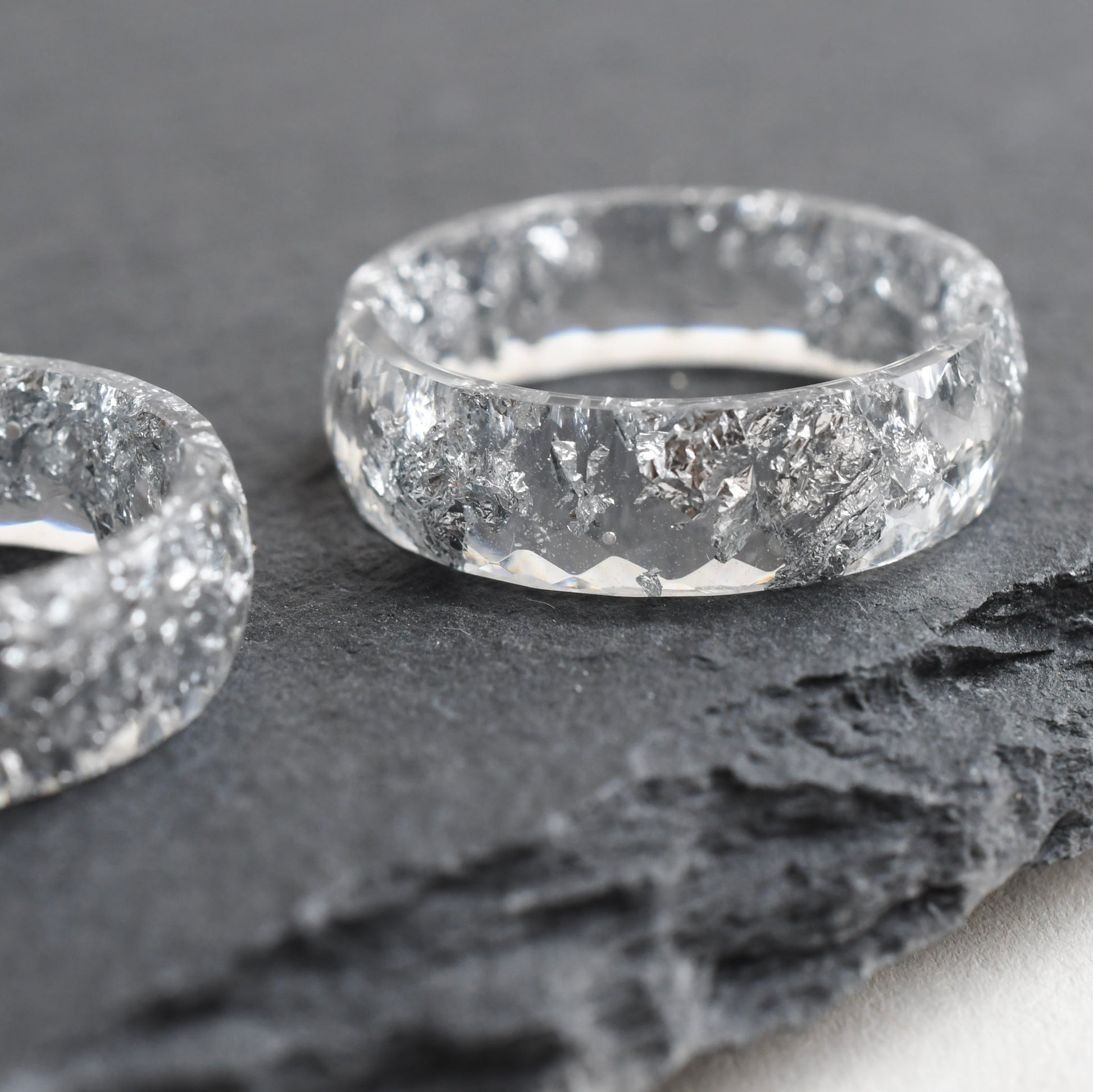 Two transparent resin with silver rings with a textured surface on a dark stone background