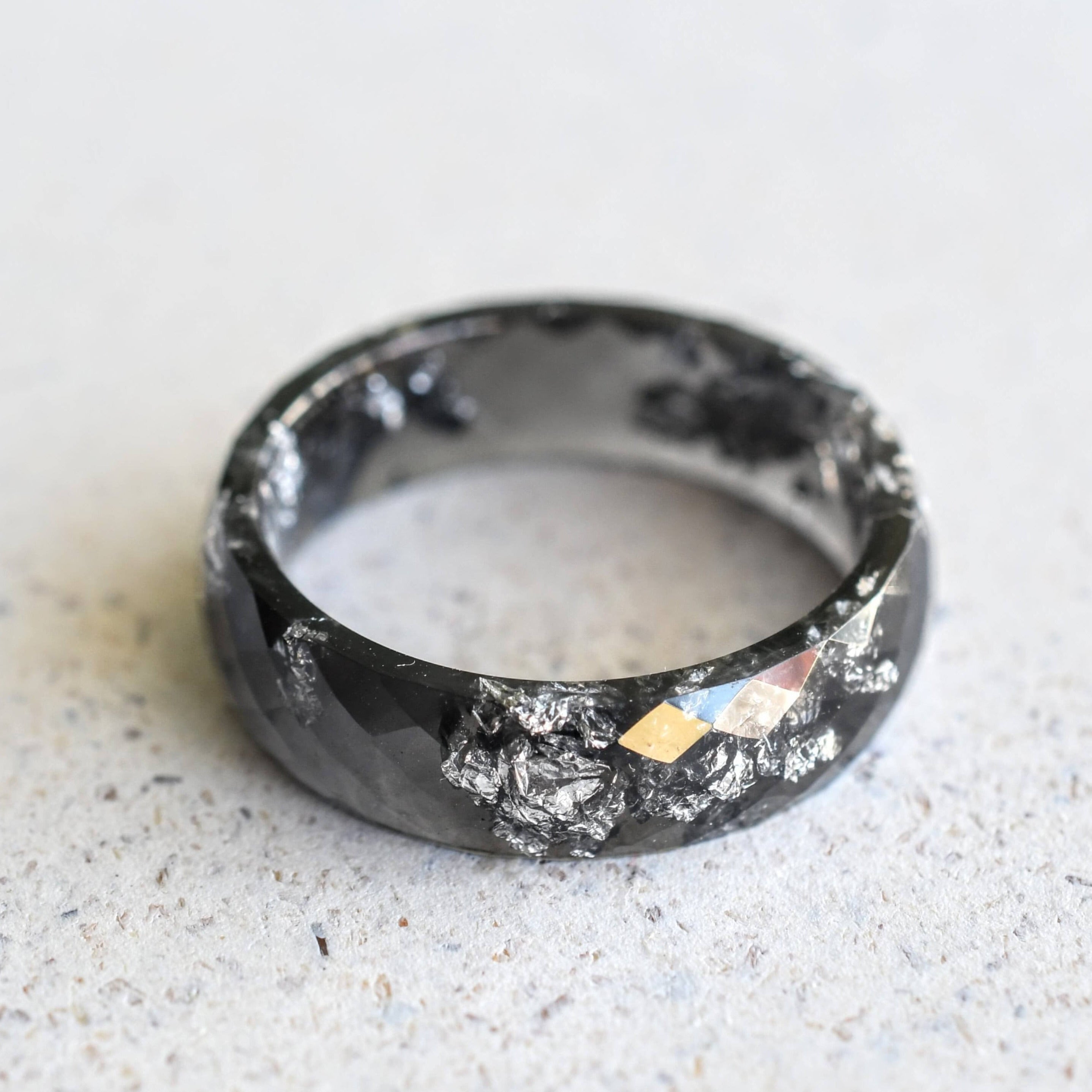 Close-up of silver flakes suspended in black resin handmade ring