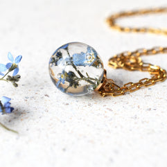 Close-up of gold-plated chain and resin with dried flowers