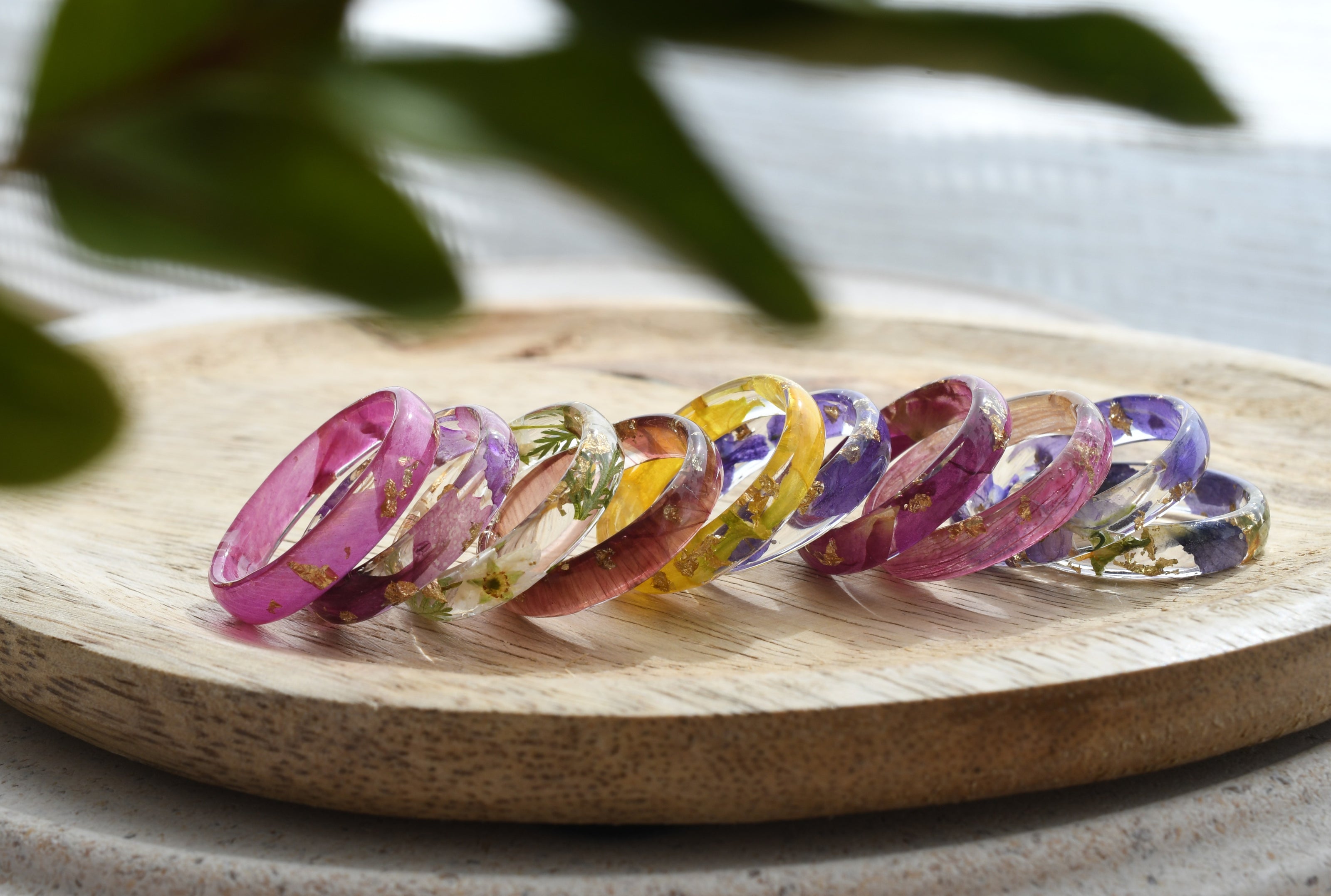 Set of colorful resin rings on a wooden surface with a natural background