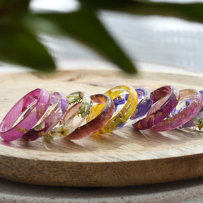 Set of colorful resin rings on a wooden surface with a natural background
