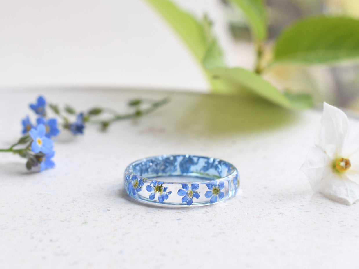 Thin resin ring with preserved blue flowers and silver leaf inclusions
