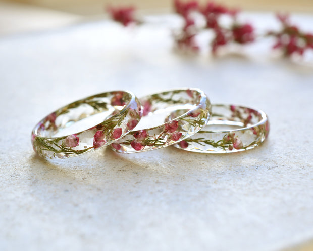 Three floral-patterned clear rings on a light surface with blurred flowers in the background