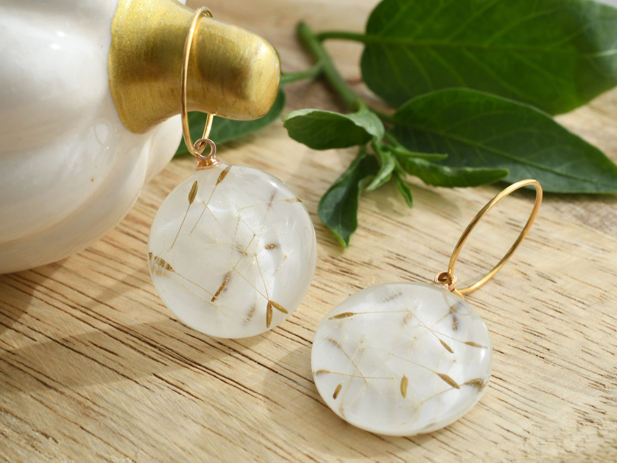 White resin earrings with floating dandelion seeds and gold hoop setting, handmade botanical jewelry