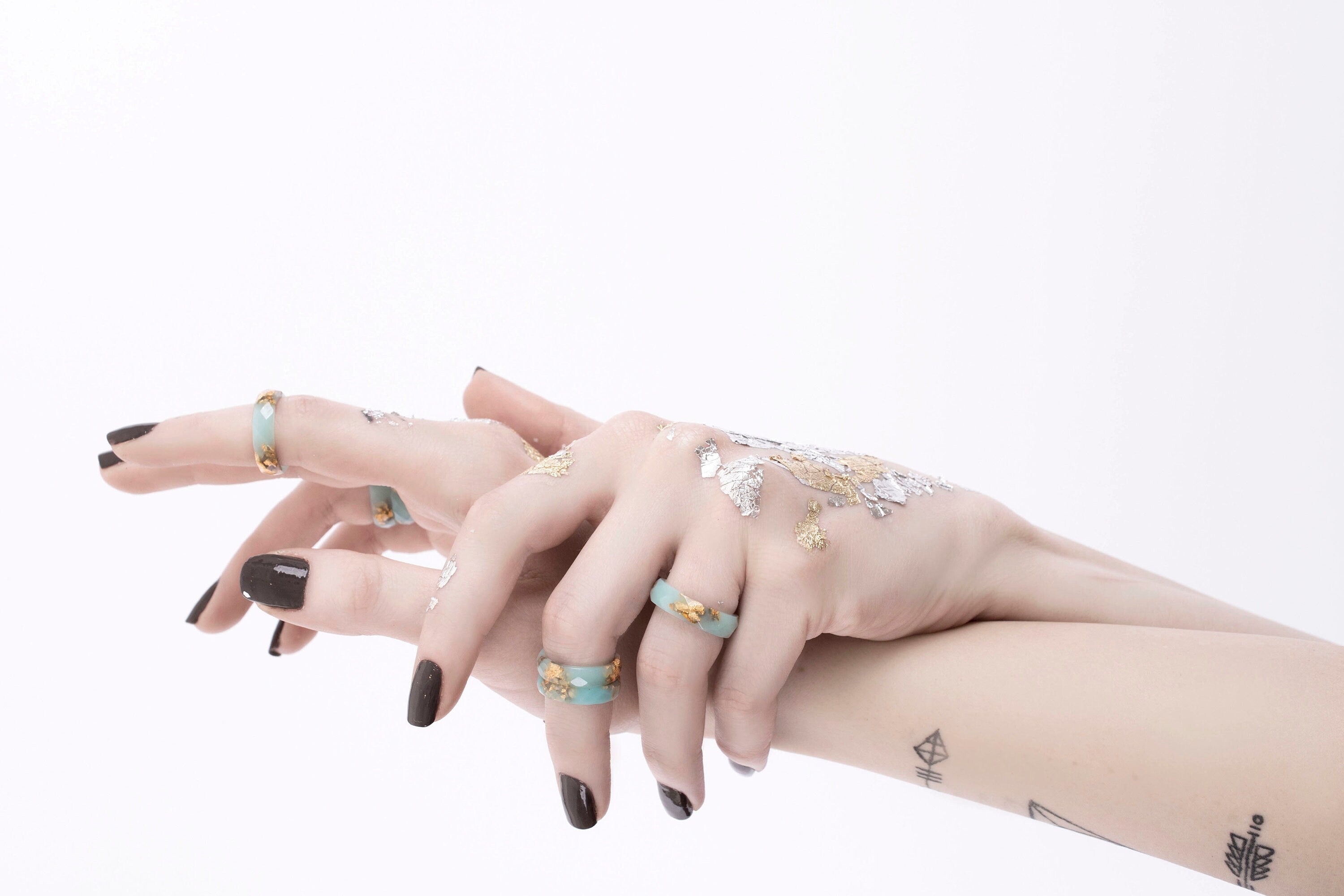 Mint ring with gold flakes on hands
