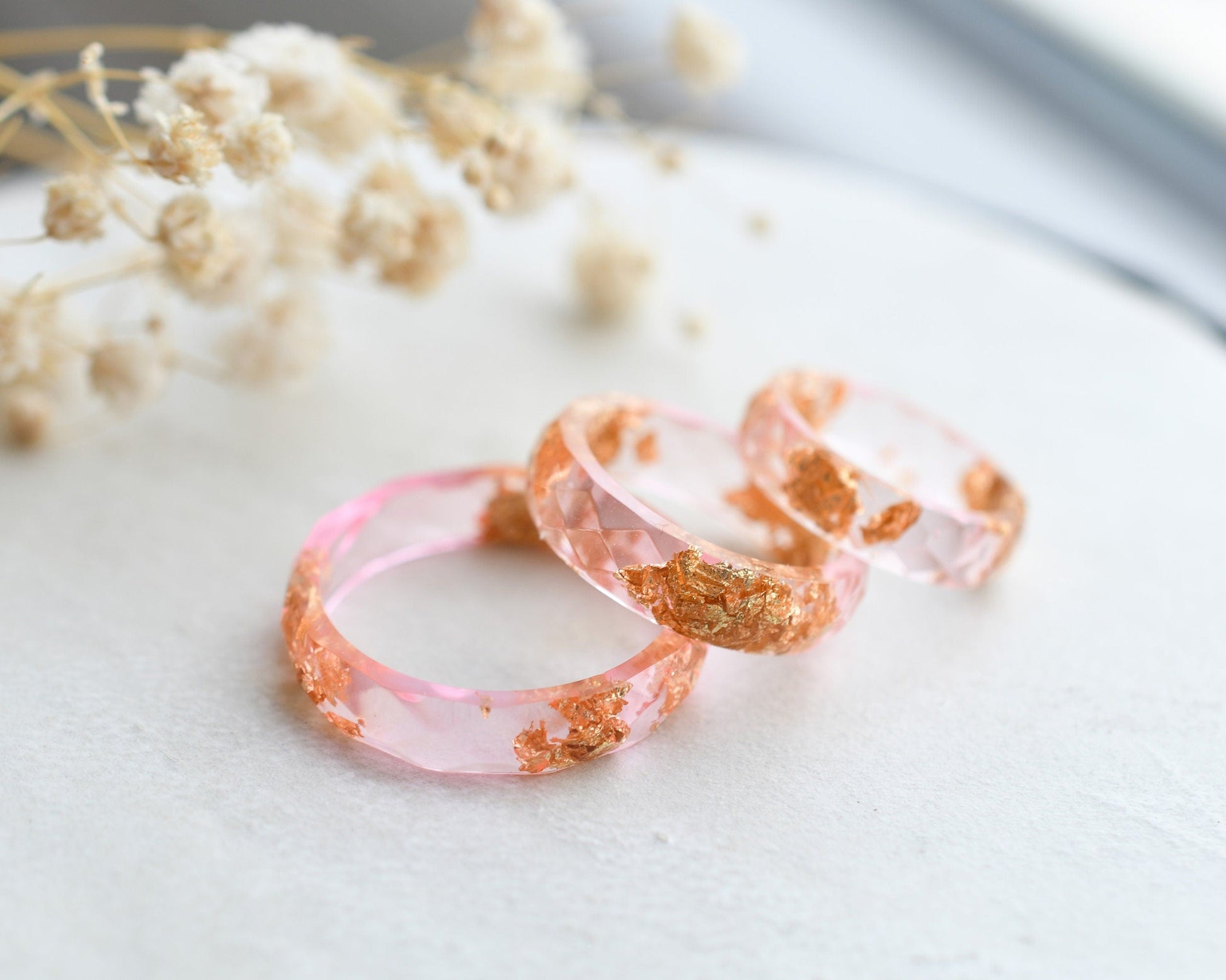 Close-up of gold flakes suspended in clear pink resin handmade ring