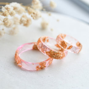 Close-up of gold flakes suspended in clear pink resin handmade ring