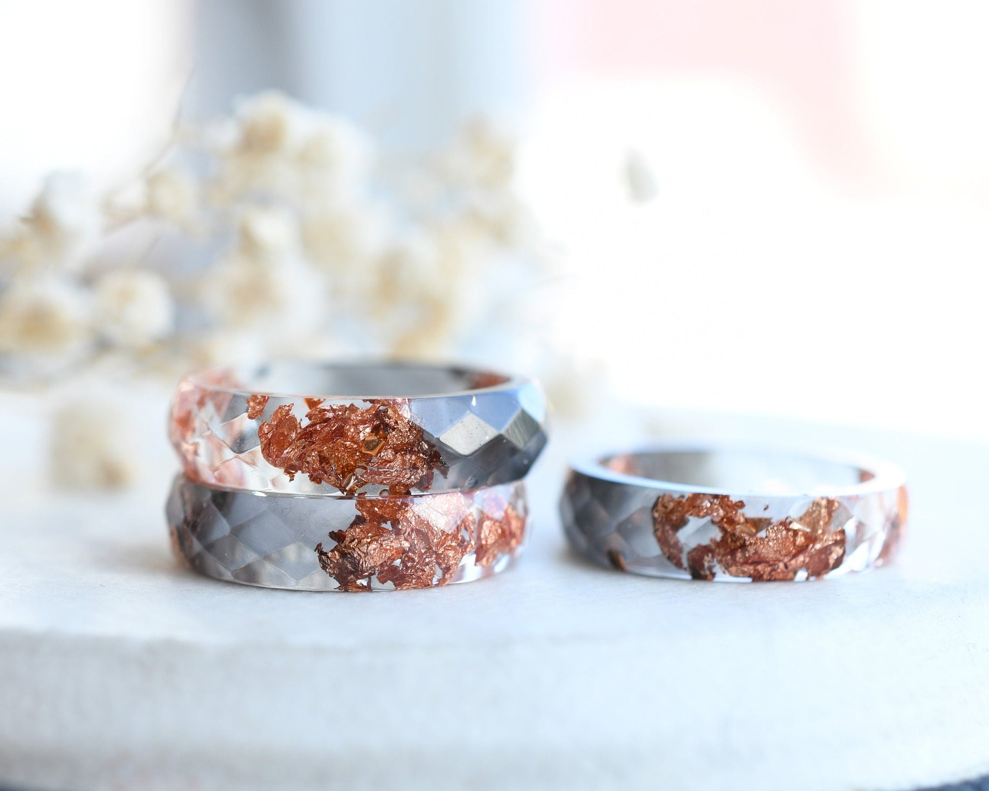 Close-up of rose gold flakes suspended in grey and transparent resin ring