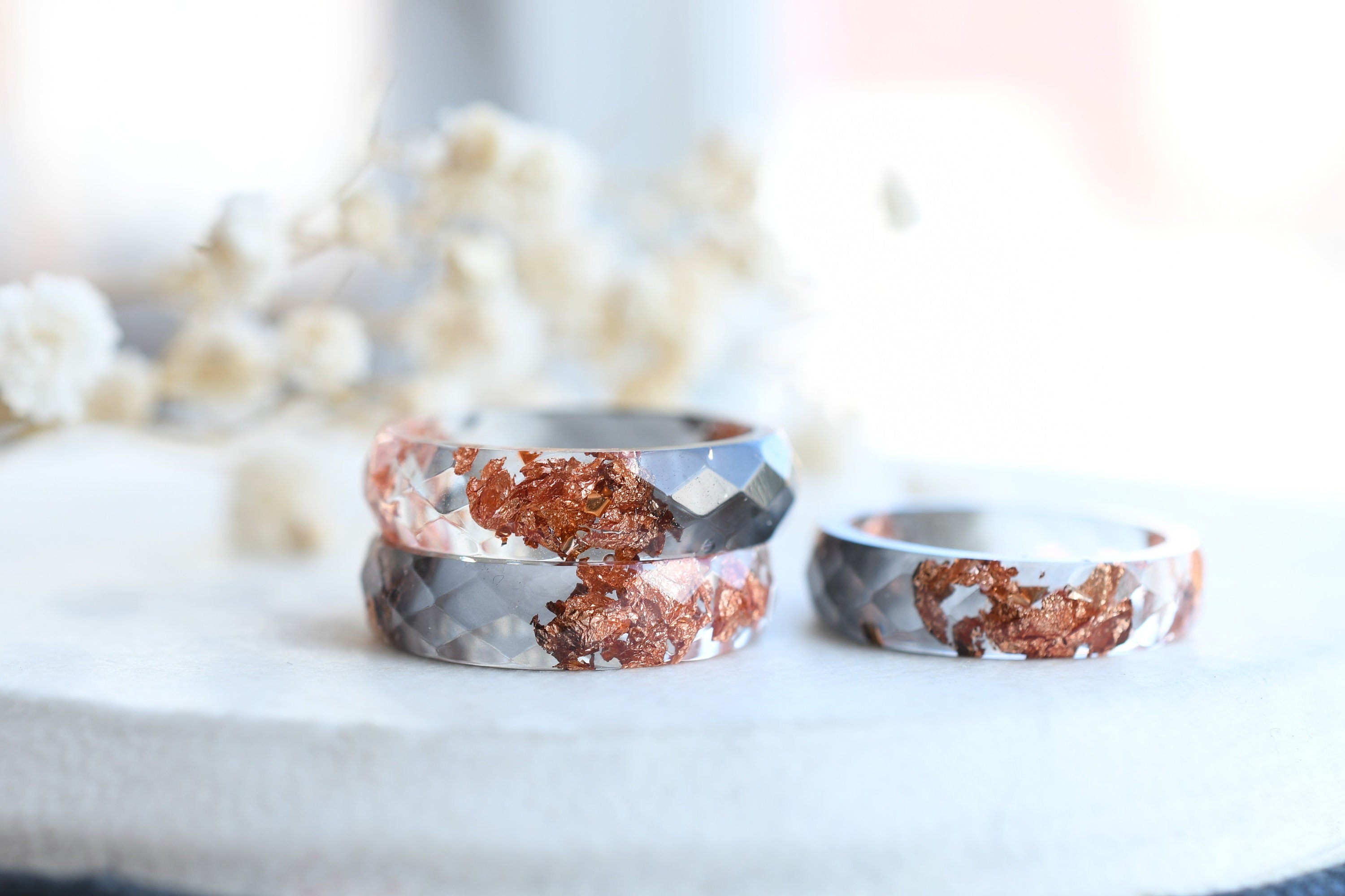 Close-up of rose gold flakes suspended in grey and transparent resin ring