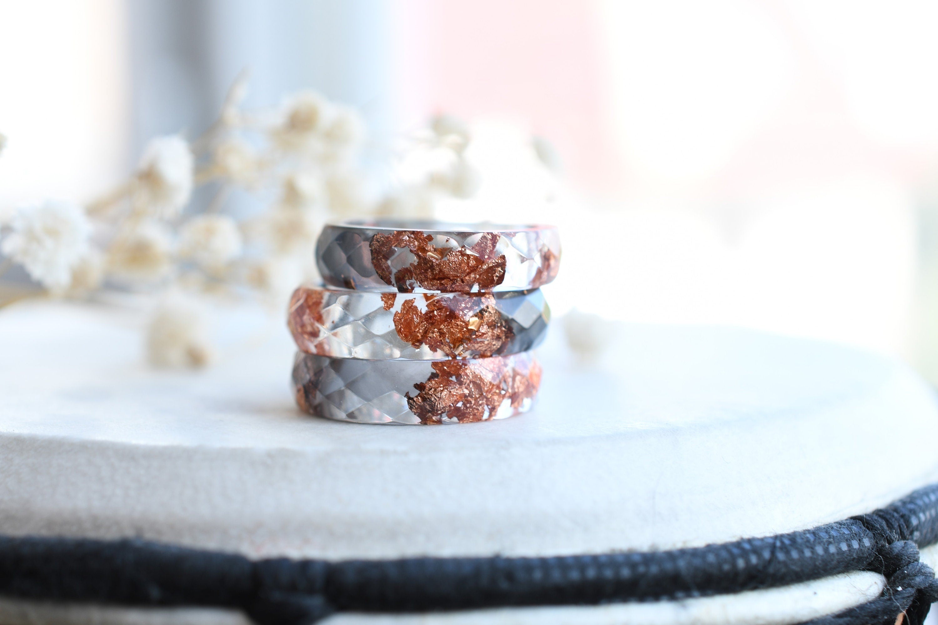 Close-up of rose gold flakes suspended in grey and transparent resin rings