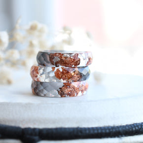 Close-up of rose gold flakes suspended in grey and transparent resin rings