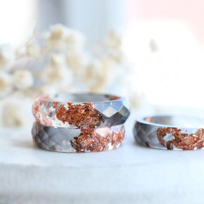 Close-up of rose gold flakes suspended in grey and transparent resin ring