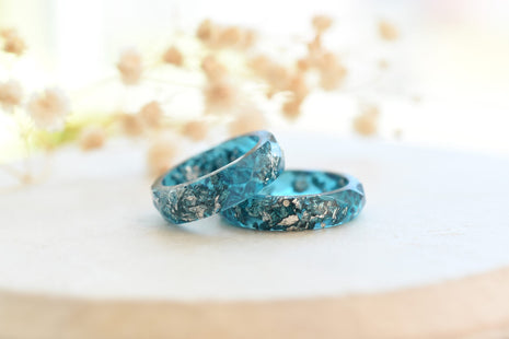 Close-up of teal resin ring with shimmering silver flakes and smooth finish