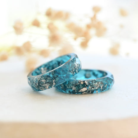 Close-up of teal resin ring with shimmering silver flakes and smooth finish